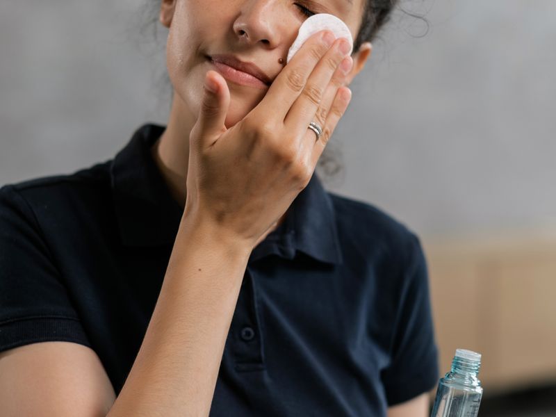 Woman pressing a cotton pad to her face