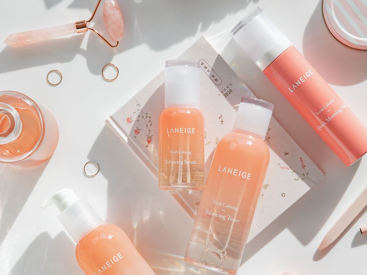 Pink skincare bottles laid out on a bright table