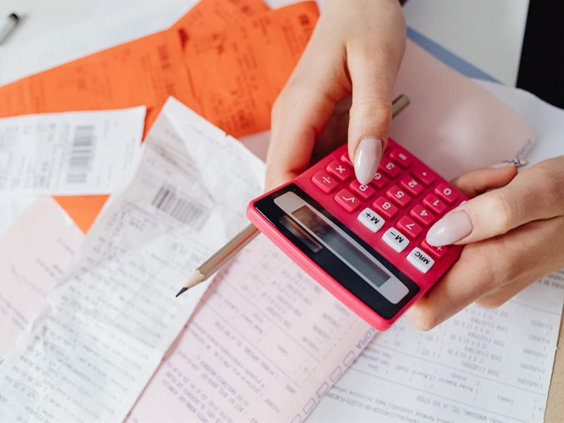 Hands using a calculator over a pile of receipts