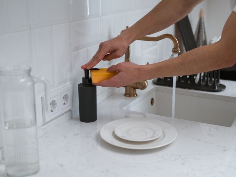 Hands pumping soap at a kitchen sink