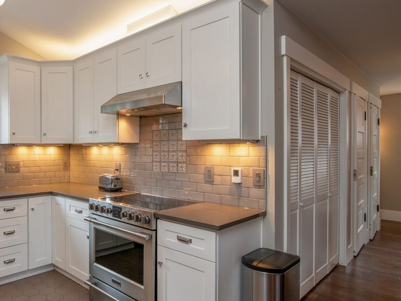 Bright white kitchen with a closed stainless steel trash can