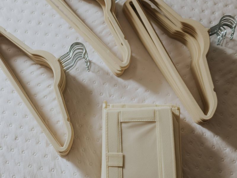 Beige velvet hangers laid out on a bed