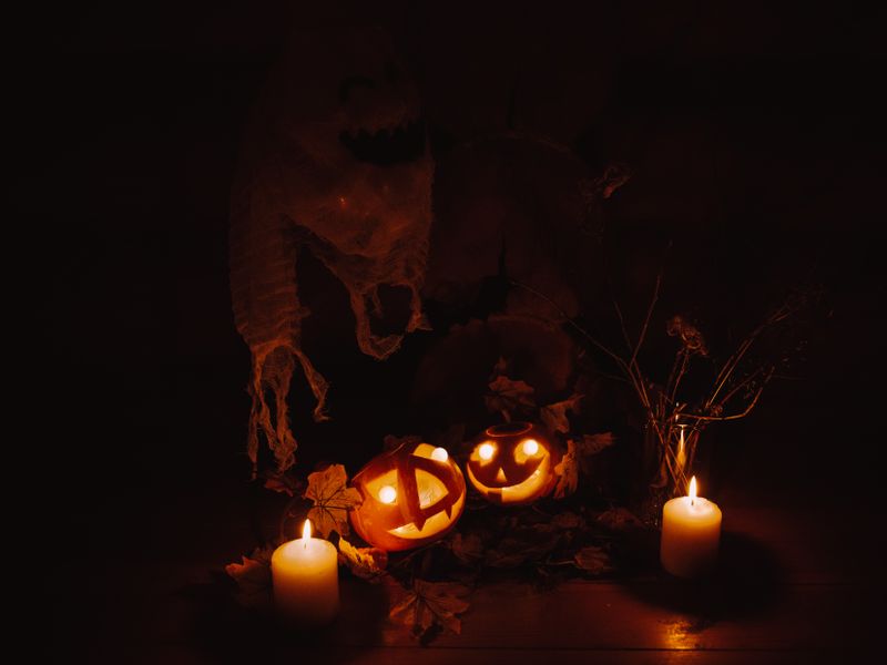 Candles glowing beside jack-o-lanterns in the dark