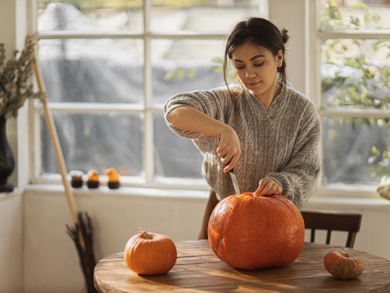 Woman carving a pumpkin at a table
