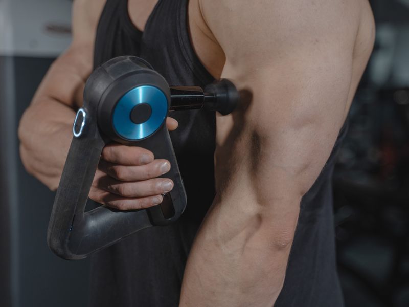 Massage gun easing a sore arm muscle
