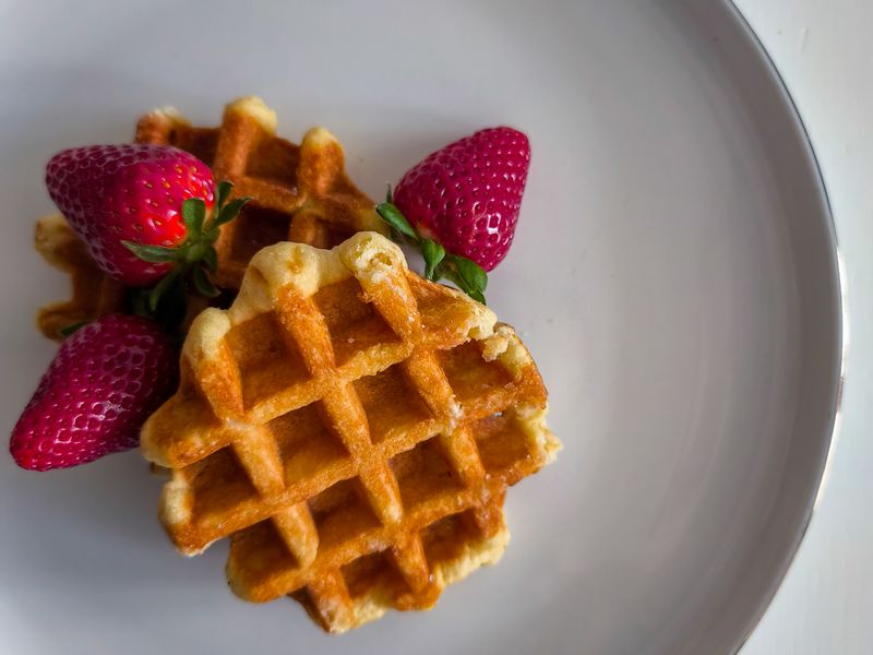 Small round waffles with fresh strawberries on a white plate