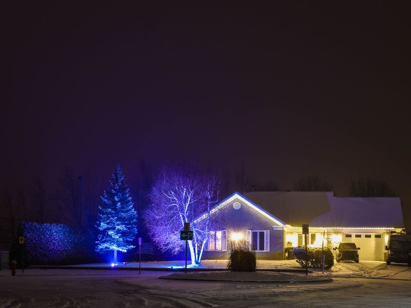 House and yard lit up with holiday lights at night